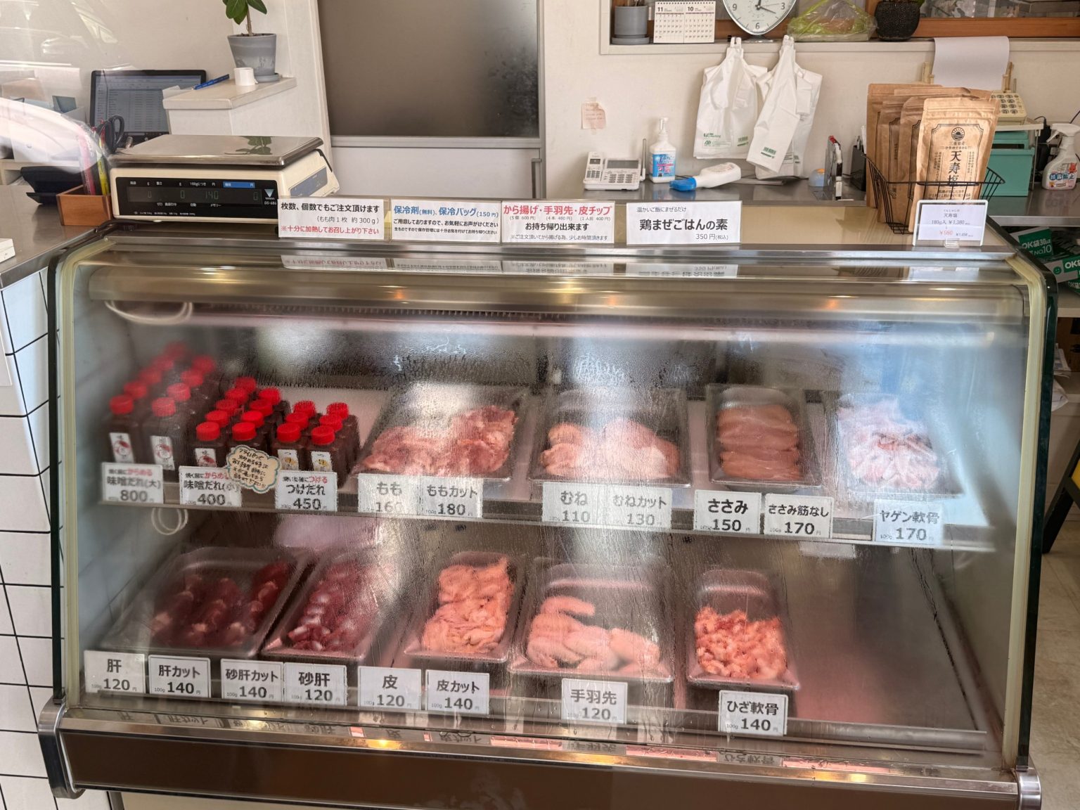Butcher counter at Shinya selling chicken cuts by the 100 g and bottles of miso sauce