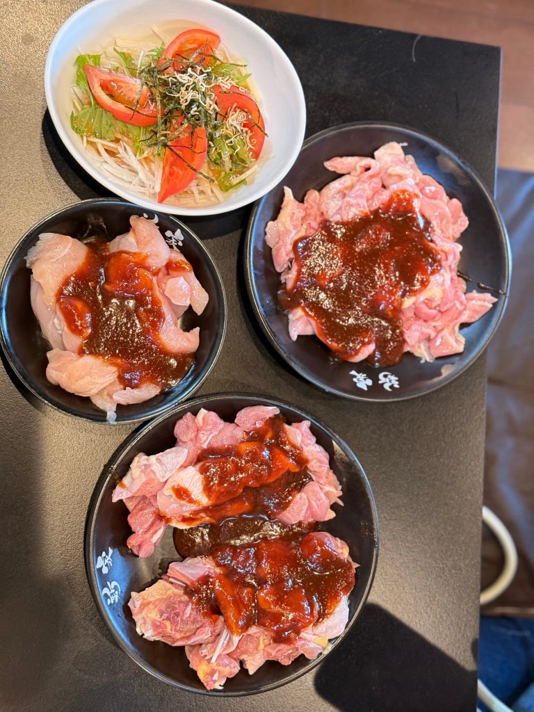 Overhead view of three plates of chicken in miso sauce and a daikon salad at Shinya, Matsusaka