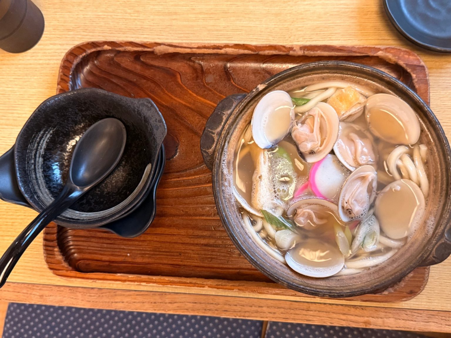 Overhead view of hamaguri nabe-udon with open clams, kamaboko and fried tofu at Kawaichi, Kuwana