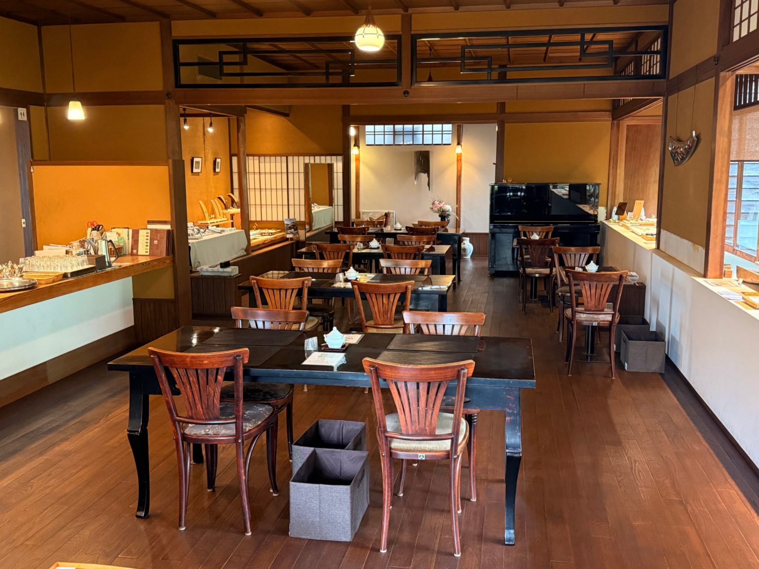 Sagan café interior with black lacquered tables, bentwood chairs and a piano