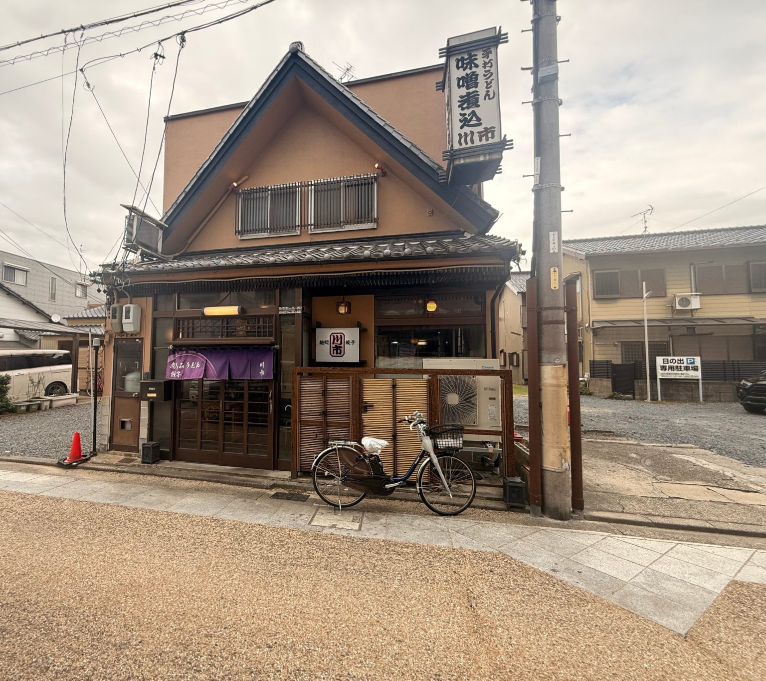 Kawaichi noodle and gyoza restaurant in Kuwana, Mie, with a purple noren and a tall miso-nikomi udon sign
