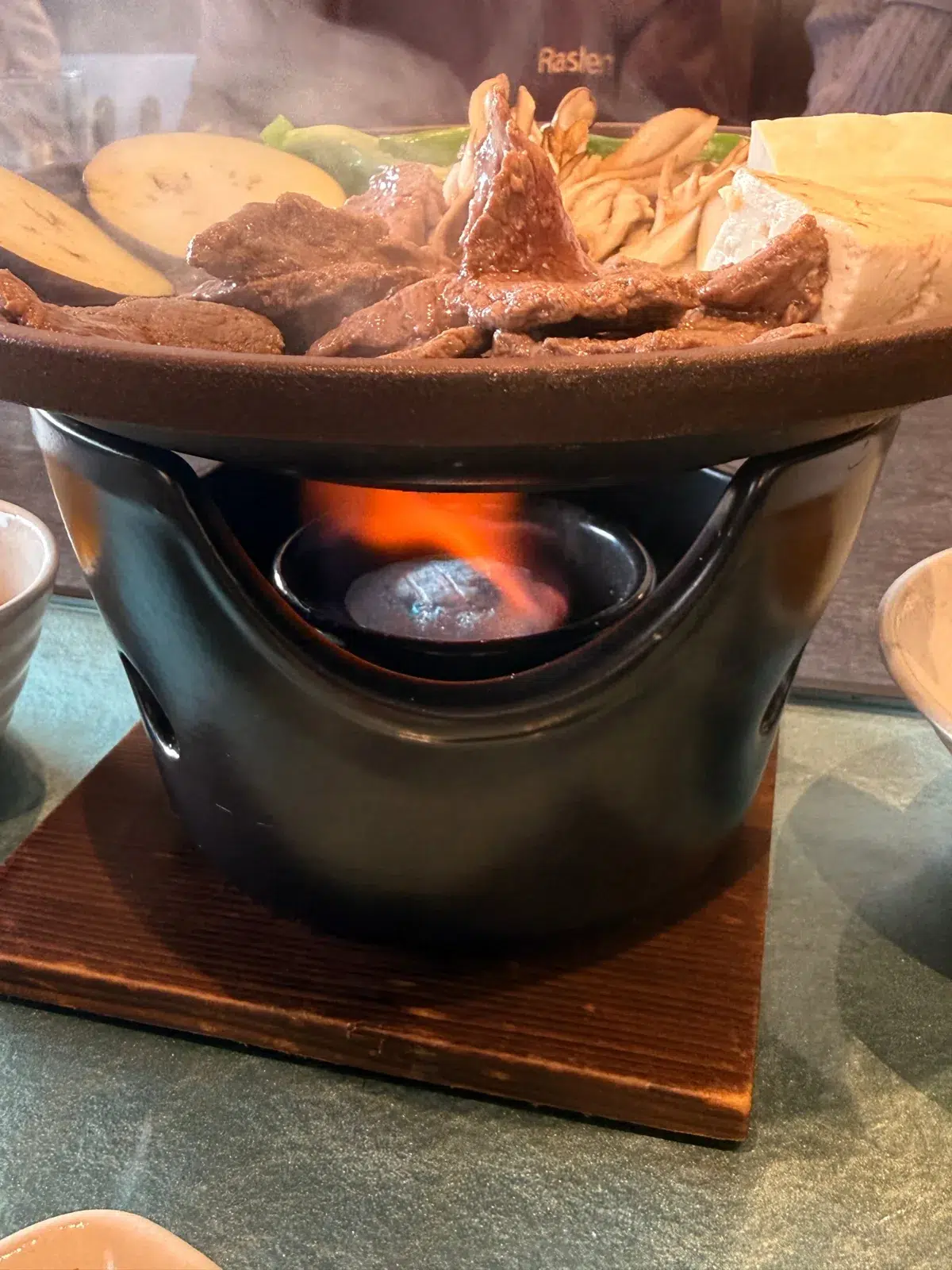 The tabletop burner under the clay pot keeps the meat cooking