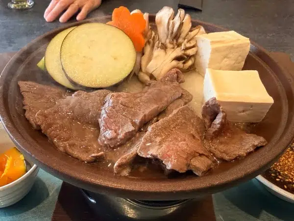 Close-up of wild deer cooking with tofu, maitake and eggplant