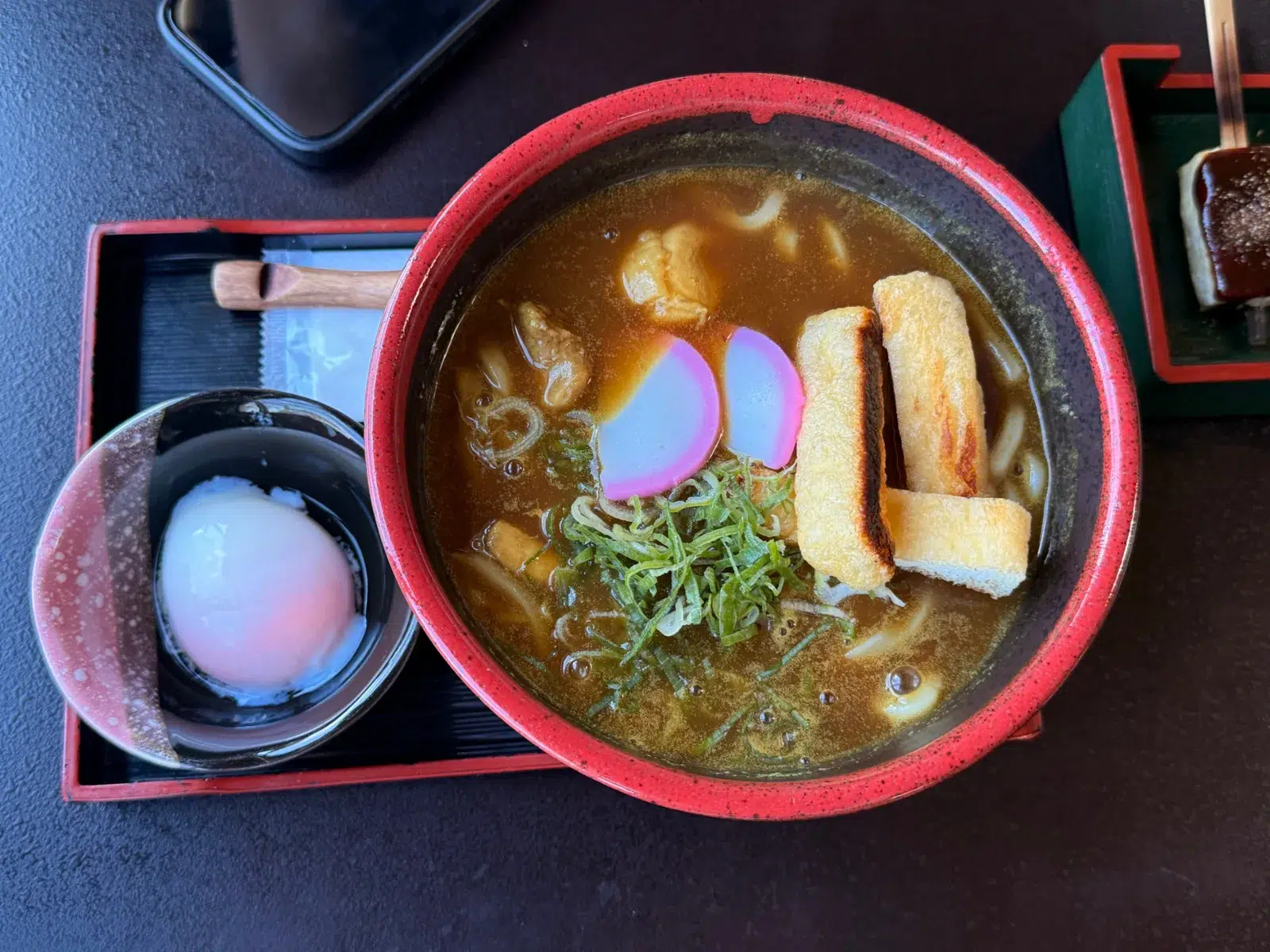 Curry udon with grilled fried tofu, kamaboko and spring onion, with an onsen egg on the side