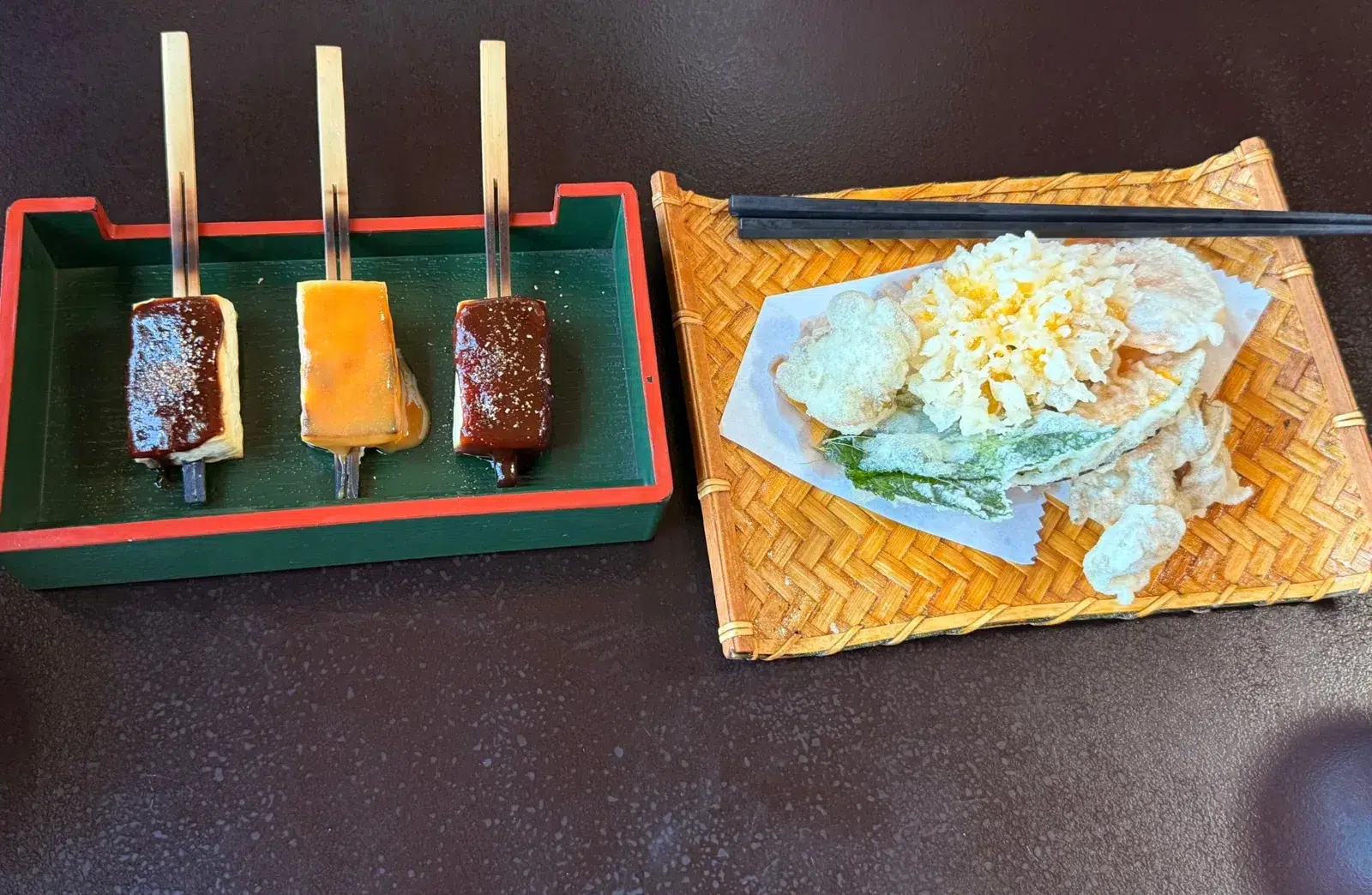 Three skewers of tofu miso dengaku beside a bamboo tray of mountain vegetable tempura